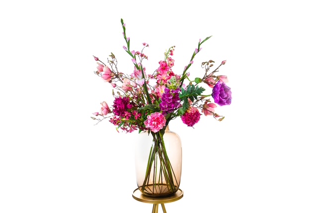 Zijden bloemstuk in roze en paars in een glazen vaas